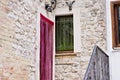 A door with a red curtain near a window with a green curtain in an italian brick house Italy, Europe Royalty Free Stock Photo