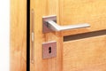 Door to a darkened room open a little, metal handle with a key hole closeup, inside shot, modern interior house wooden door gap Royalty Free Stock Photo