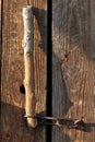 The door to the old barn is closed on a chain. A wooden stick is inserted into the loop