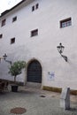 Door, with wrought iron grille and two lampposts on the sides, in a white wall on which small windows open at the top, in Graz. Royalty Free Stock Photo