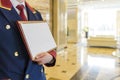 The doorman in the lobby of the hotel holding a sign