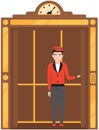 Doorman standing inside cabin of mechanical retro lift. Elevator with doors and floor counter