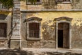 Doors and windows in a weathered, peeling yellow wall