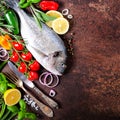 Dorada, fresh fish with vegetable, lemon, herbs, onion, paprika, cherry tomatoes, onion, salton dark vintage background. Copy spac Royalty Free Stock Photo