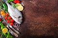 Dorada, fresh fish with vegetable, lemon, herbs, onion, paprika, cherry tomatoes, onion, salton dark vintage background. Copy spac Royalty Free Stock Photo