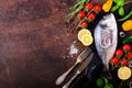 Dorada, fresh fish with vegetable, lemon, herbs, onion, paprika, cherry tomatoes, onion, salton dark vintage background. Copy spac Royalty Free Stock Photo