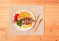 Dorado  fish with lemon, fried potatoes, fresh parsley and tomatoes on white plate on wooden table. Royalty Free Stock Photo