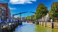 View over water canal on typical dutch old drawbridge, boats and old houses against blue summer sky Royalty Free Stock Photo