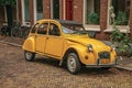 Elegant brick street with typical houses, plant and vintage yellow car in Dordrecht.