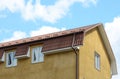 Dormer windows on metal roof. A house with a roof made of metal roofing with mansard windows and rain gutter. Royalty Free Stock Photo