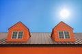 dormer with windows on metal sheet roof with blue sky and sunshine Royalty Free Stock Photo