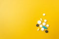 Dose of multicolored pills and capsules isolated on yellow background on the right side. Drug treatment and healthcare.