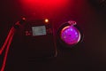 Dosimeter of radioactive radiation next to an old pocket watch with dangerous fluorescent paint. Violet light and green glow of