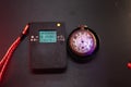 Dosimeter of radioactive radiation and old broken pocket watch with dangerous fluorescent paint. Violet light and green glow of