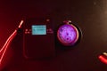 Dosimeter of radioactive radiation and old broken pocket watch with dangerous fluorescent paint. Violet light and green glow of