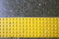 Close up yellow braille block on dark granite tile floor