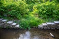 Double antique stone steps by green lush woodland descend to calm water stream