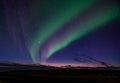 Double band northern lights in Iceland. Rocky foreground with the last glimmer of sun on the horizon. Deep blue, Purple and green Royalty Free Stock Photo