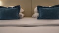 On the double bed, made with clean sheets, white and blue decorative pillows are stacked in a pile. Royalty Free Stock Photo