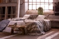 Bed with pillows and blanket, wooden stool and plant in a wabi sabi bedroom