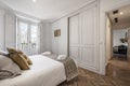 Double bedroom with beautiful decoration in hardwood, white fitted wardrobes, matching blanket and cushions, herringbone oak