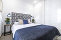 Double bedroom decorated in blue and white tones with natural plants on the side tables and a large built-in wardrobe