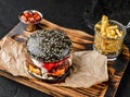 Double black burger with two beaf meat patties, slice of cheese, mayonnaise and berry sauce on wooden board with french fries Royalty Free Stock Photo