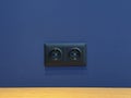 Double black designer socket in blue wall Royalty Free Stock Photo