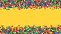 Double border of colorful coated chocolate candies on yellow background