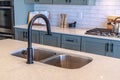 Double bowl sink and black faucet on kitchen island against cooktop and counter