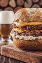 Double burger with cheddar cheese, a glass of beer and firewood pile in background - Close-up Royalty Free Stock Photo