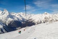 Double-chair ski lift with people over the ski slopes on the background of the Caucasus Mountains ridge on a sunny winter day Royalty Free Stock Photo