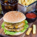 Double cheese burger with caramelized onion, lettuce and jalapeno, served with french fries and soda, on a wooden board, square, Royalty Free Stock Photo