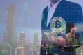 Double exposure of businessman holding bitcoin on hand and defocused chart background with modern city background. Royalty Free Stock Photo