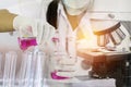 Scientist woman research carrying chemistry liquid with microscope equipment for research experiments to test tube Royalty Free Stock Photo