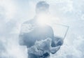 Double exposure clouds young bearded businessman wearing black shirt and holding contemporary notebook hands. White empty screen r