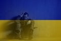 Double exposure of frustrated military soldier sitting crying alone in boot camp and Ukrainian flag.