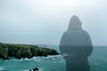 A double exposure of a hooded figure looking out at a moody rugged coast in winter.