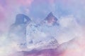 A double exposure of a hooded figure looking at a snow covered mountain peak. With an abstract, experimental dream like edit