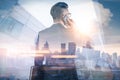 The double exposure image of the businessman using a smartphone during sunrise overlay with cityscape image. Royalty Free Stock Photo