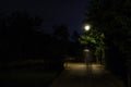 Double exposure night scene of person walking dark street illuminated with streetlights. The receding male silhouettes