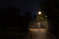 Double exposure night scene of person walking dark street illuminated with streetlights. The receding male silhouettes