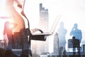 Double exposure of a professional woman using laptop with a transparent cityscape overlayed Royalty Free Stock Photo