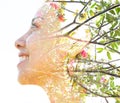 Double exposure close up profile portrait of a young pretty woman interwoven with tree branches and delicate colorful flowers Royalty Free Stock Photo