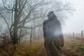 A double exposure of a spooky silhouette of a woman. On a country path next to a line of trees on a moody misty winters day