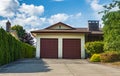 Double garage with short driveway in a summer. Family house with wide garage door and concrete driveway in front