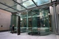 Double modern frameless glass revolving doors covered by canopy glazing to office building lobby