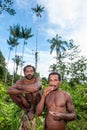 The double Portrait Korowai men on the natural green forest background.