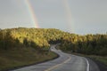 Double rainbow above road curving through hills in northern Minn