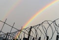 Double rainbow behind rows of a barbed wire. LGBTQ freedom suppression concept Royalty Free Stock Photo